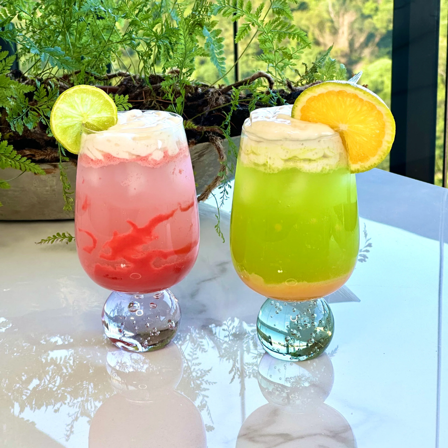 Duas taças com bebidas coloridas e fatias de frutas decorativas