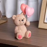 Urso Teddy em resina bege sentado na mesa com balões rosa e coral