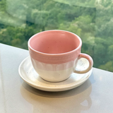 xícara de chá cerâmica ombre rosa e branco com pires em superfície cinza