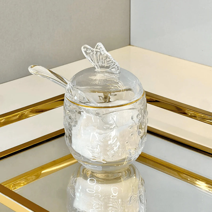 Açucareiro de vidro com detalhe dourado sobre bandeja espelhada dourada