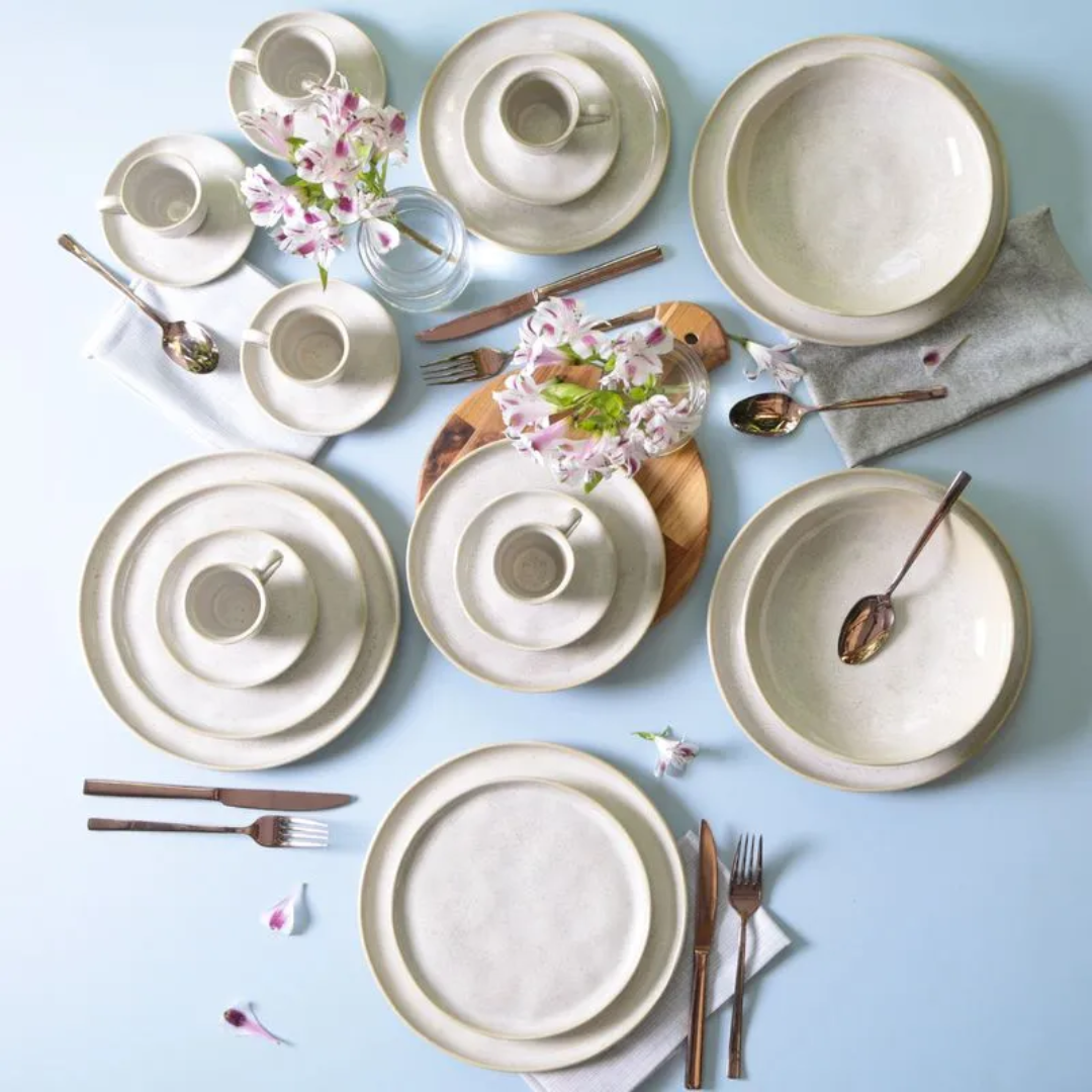 Mesa posta com aparelho de jantar em louça com flores e talheres