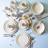 Mesa posta com aparelho de jantar em louça com flores e talheres