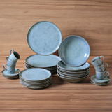 Conjunto completo de louça azul com pratos, tigelas e xícaras organizados sobre madeira
