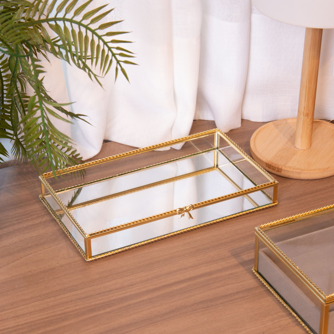 Bandeja espelhada dourada sobre mesa de madeira com decoração minimalista