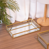 Bandeja espelhada dourada sobre mesa de madeira com decoração minimalista