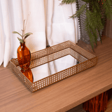 Bandeja de metal dourado com espelho em ambiente de decoração
