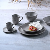 Bowl cinzento acompanhando conjunto de louça em mesa branca
