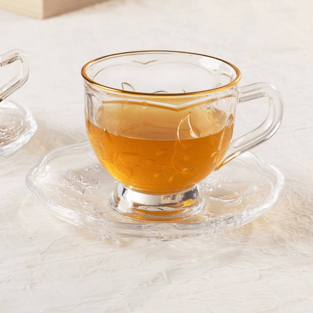 xicara de chá com borboleta de vidro e cristal com pires na mesa de café da amanhã