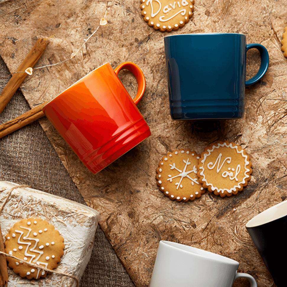 canecas laranja azul marinho na mesa com biscoitos de natal 