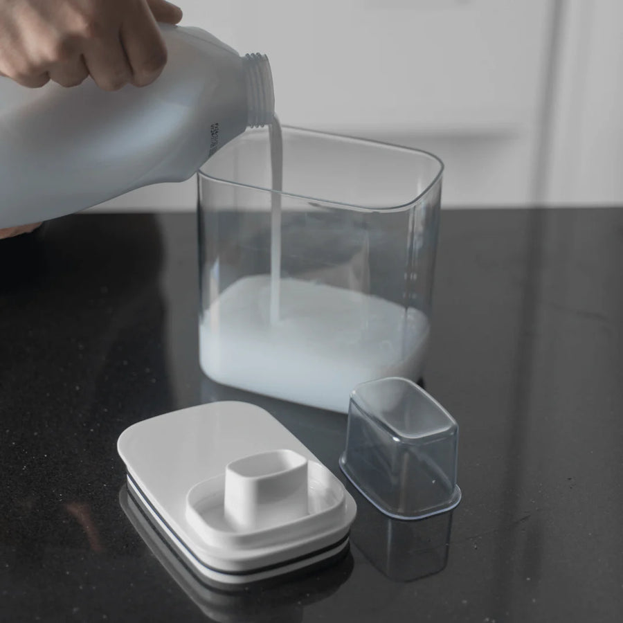 Pessoa transferindo liquido para pote dispenser com medidor separado