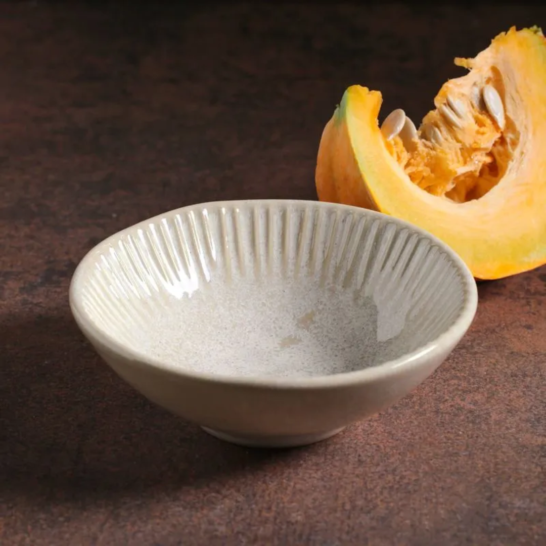 Bowl de cerâmica latte com linhas em relevo ao lado de abóbora cortada