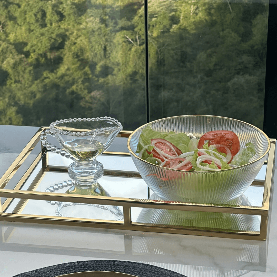 bowl de vidro canelado e uma molheira pearl em uma bandeja dourada na mesa 