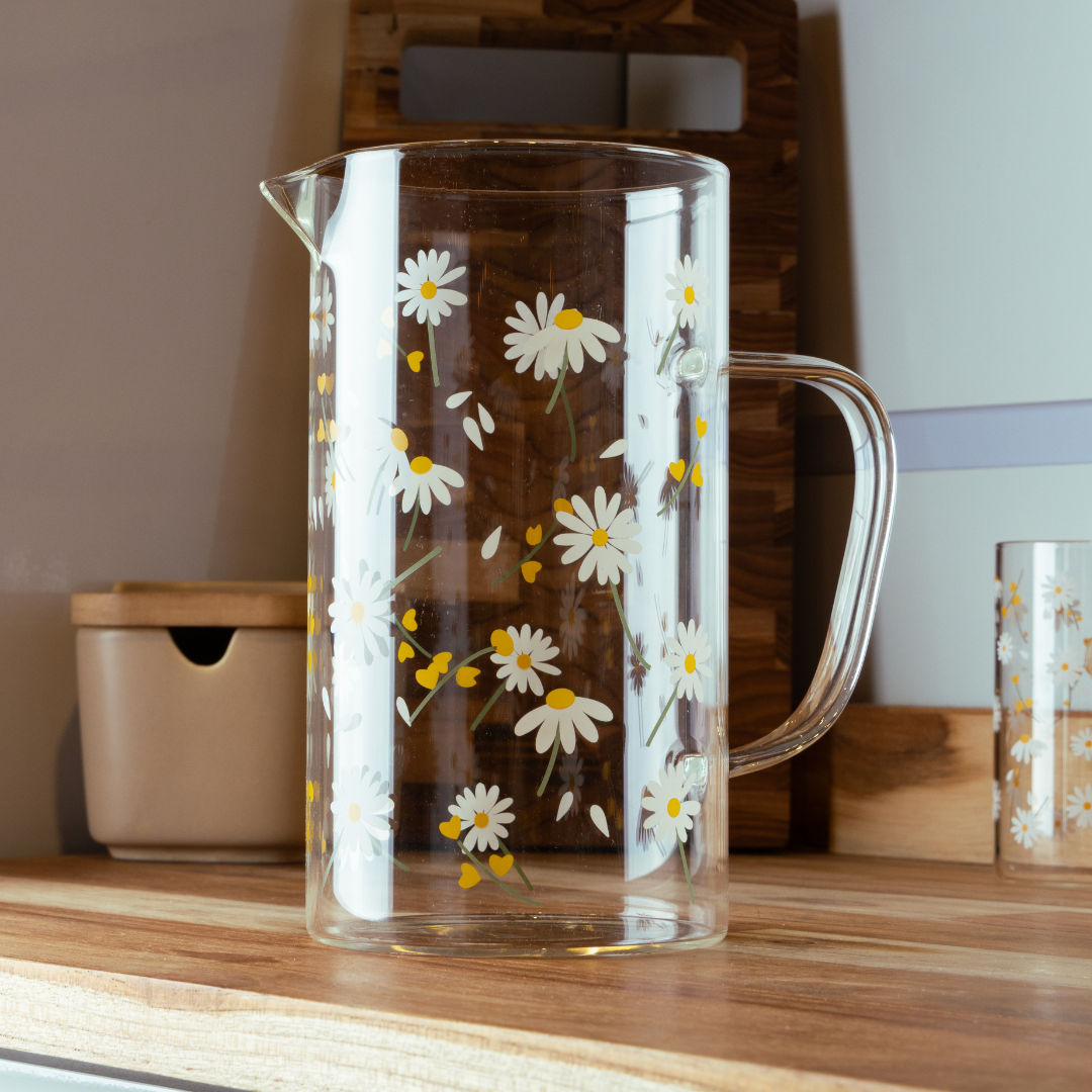 Jarra vidro borossilicato com estampa margaridas sobre mesa de madeira