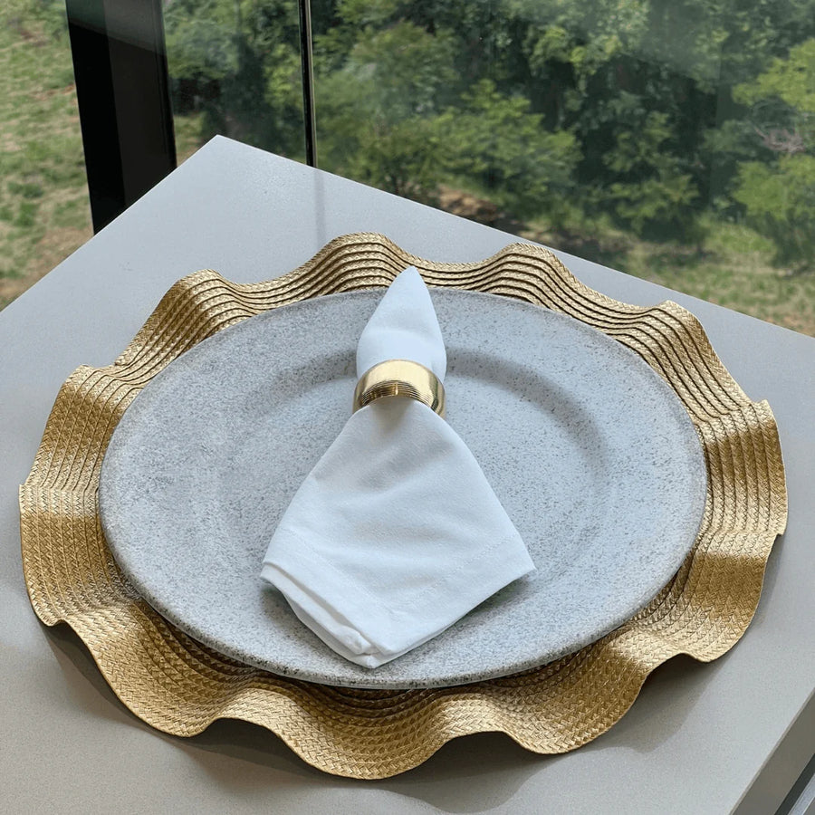 Mesa posta com jogo americano dourado babado e prato cinza com guardanapo branco