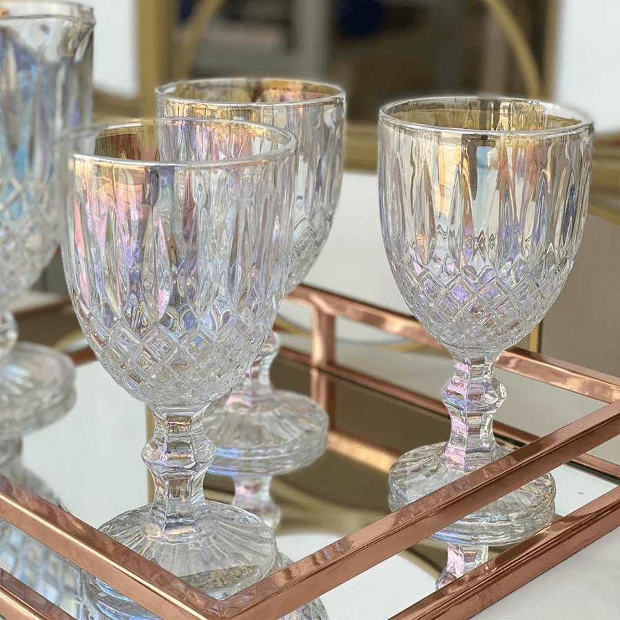 Tacas de vidro com acabamento furta-cor sobre bandeja espelhada rose gold