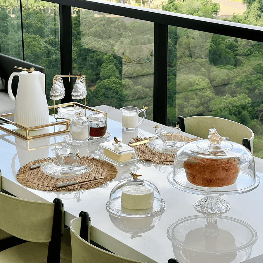 Mesa posta com boleira vidro entre outros acessórios de café