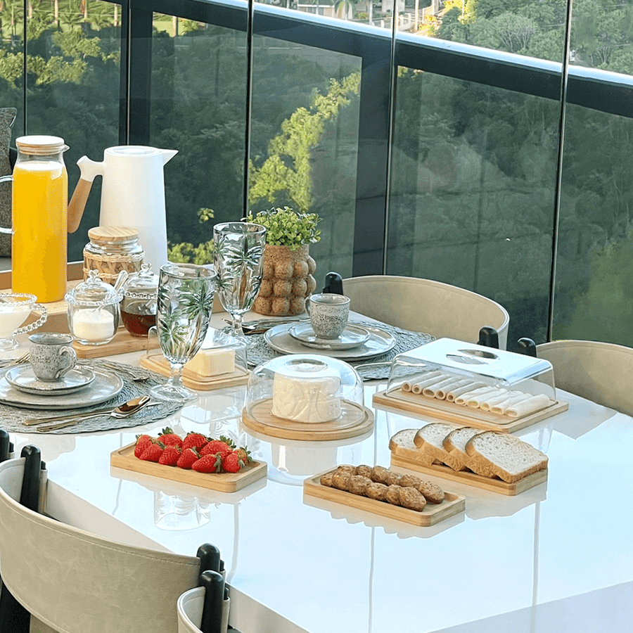 Mesa posta com bandejas de bambu servindo frutas, pães e petiscos variados