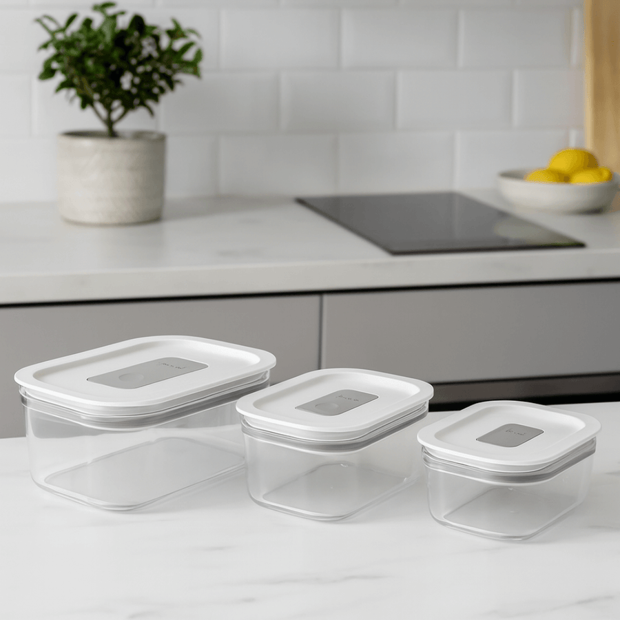 Tres potes hermeticos transparentes com tampa branca sobre bancada de cozinha moderna