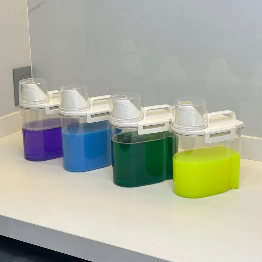 quatro potes herméticos transparentes com liquido colorido em bancada branca