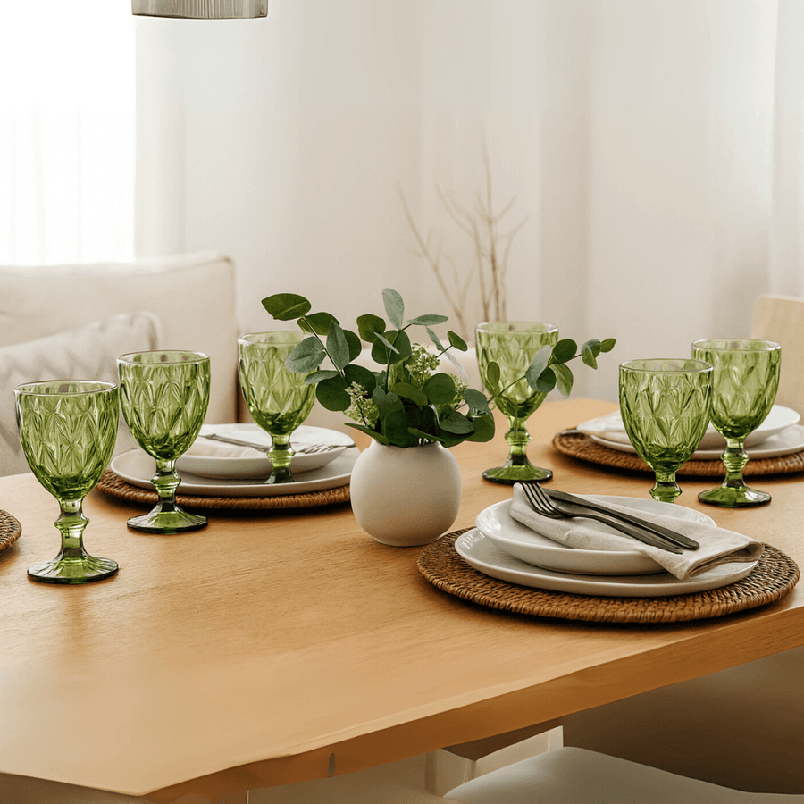 Mesa de jantar decorada com tacas de vidro verde e pratos brancos
