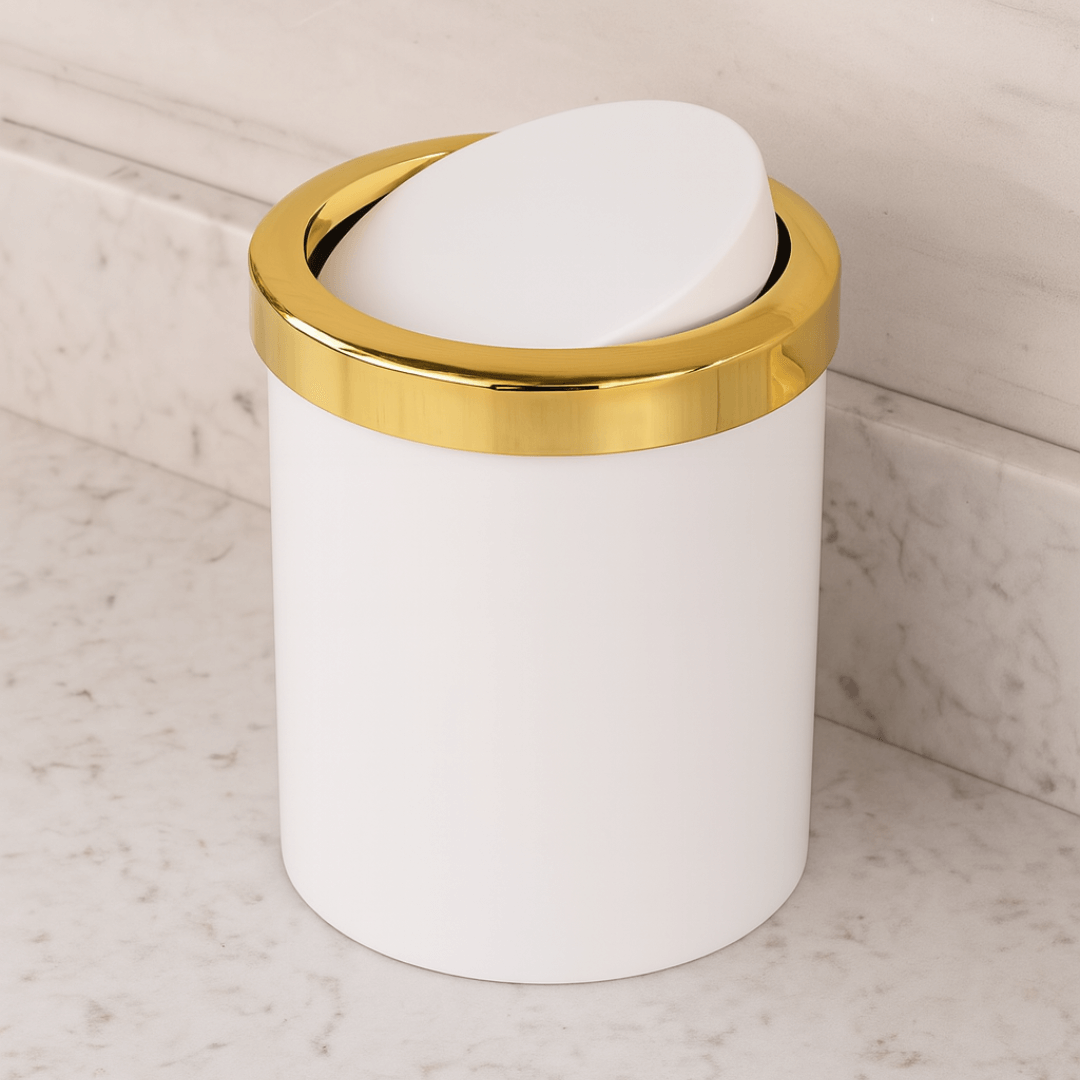 lixeira com tampa basculante branca e dourada na bancada com porcelanato