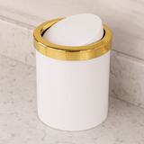 lixeira com tampa basculante branca e dourada na bancada com porcelanato