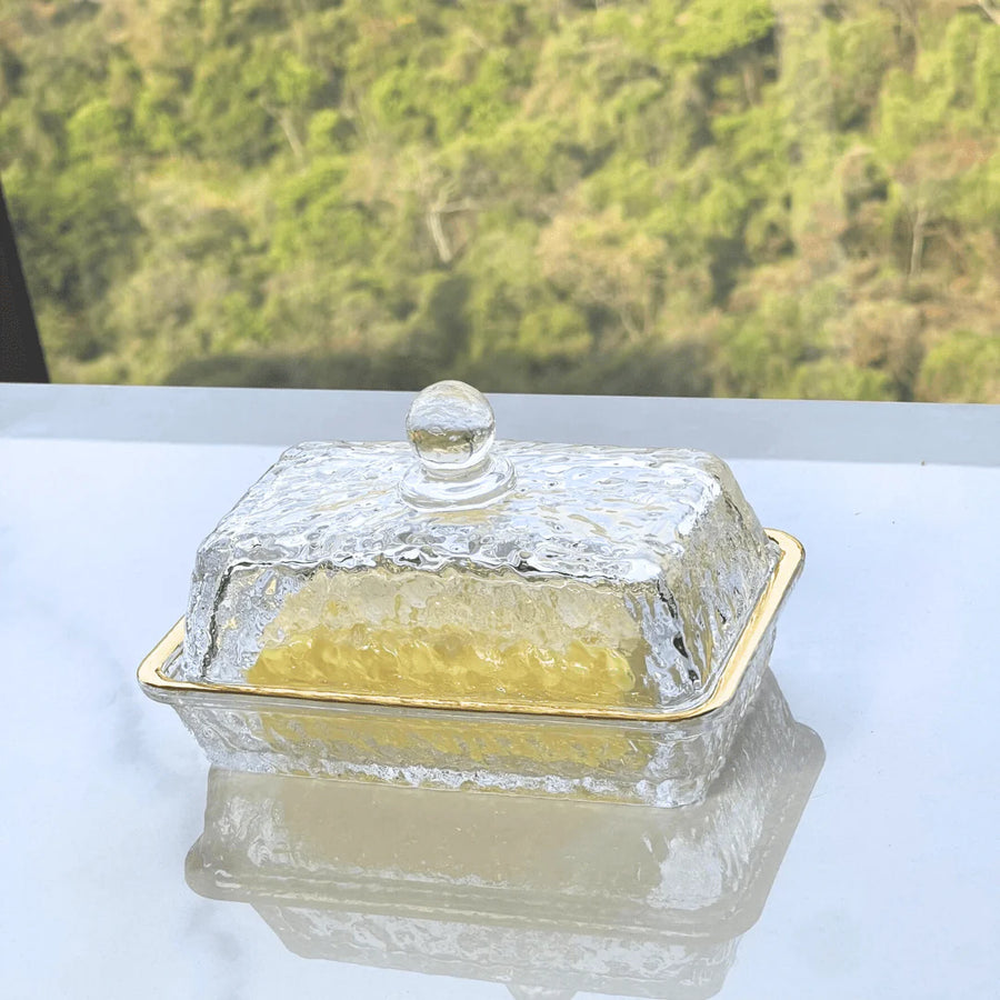 Manteigueira retangular de cristal martelado com filete dourado sobre superficie branca