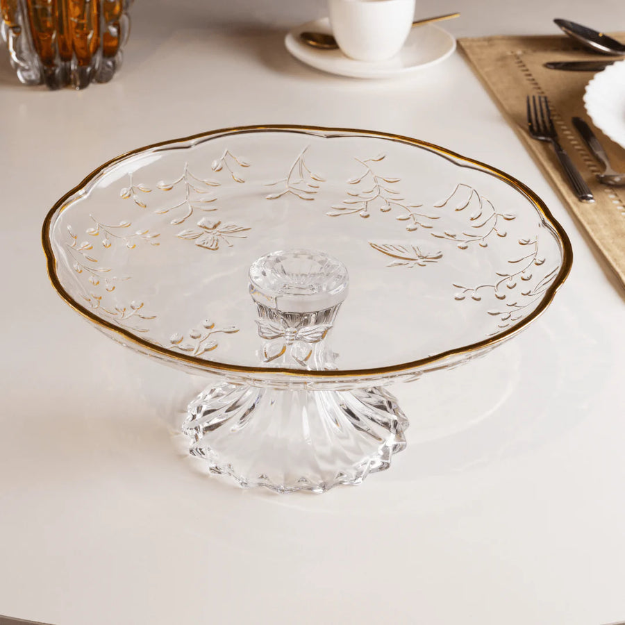 Boloeira de vidro com borda dourada e pe facetado em mesa com talheres
