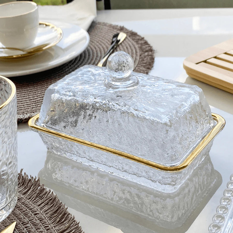 Manteigueira de cristal com borda dourada em mesa posta com sousplat de palha