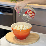 Pipoqueira sendo esvaziada em tigela laranja na cozinha