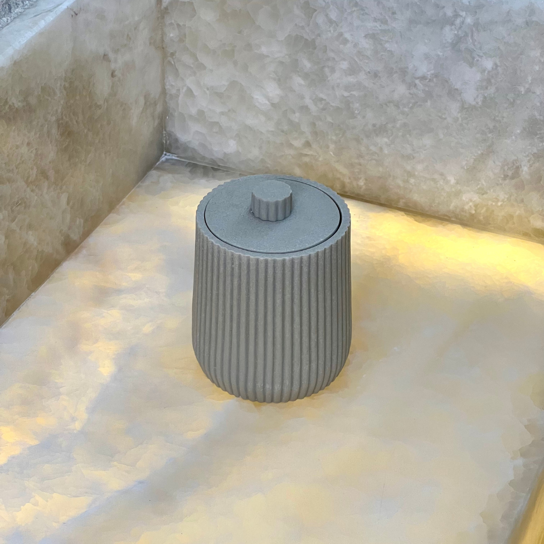 Porta cotonete bege com tampa sobre bancada iluminada