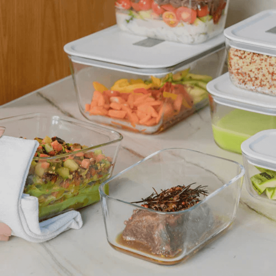 Varios potes de vidro com tampa branca sobre bancada de marmore com alimentos