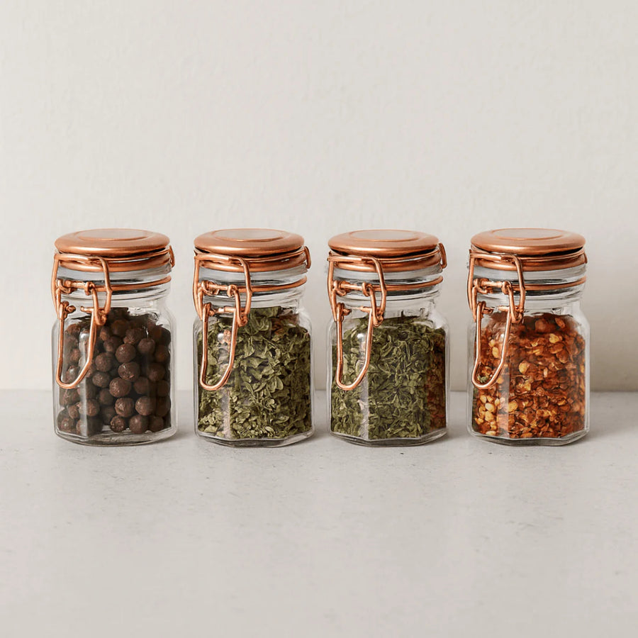 quatro porta temperos herméticos de vidro com pimenta ervas e pimenta vermelha em superficie clara
