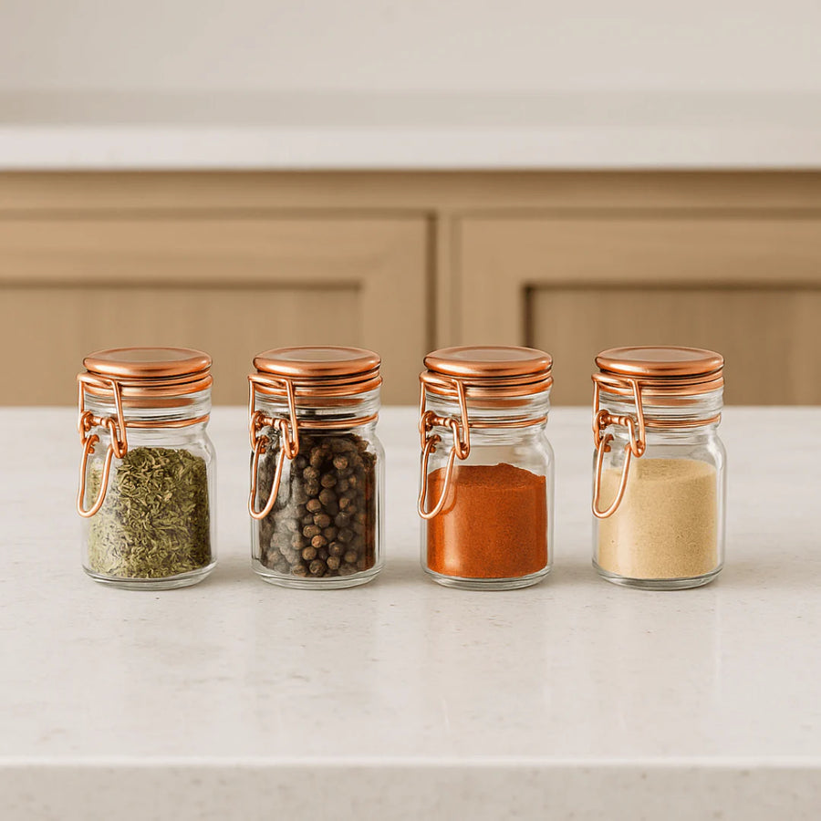 potes de vidro com fechamento hermético rose gold organizados em bancada de marmore com cozinha ao fundo