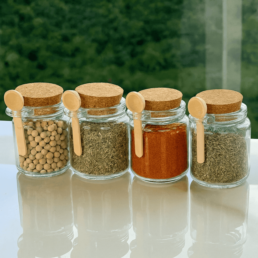 Quatro potes vidro com tampa rolha e colher bambu cheios de condimentos