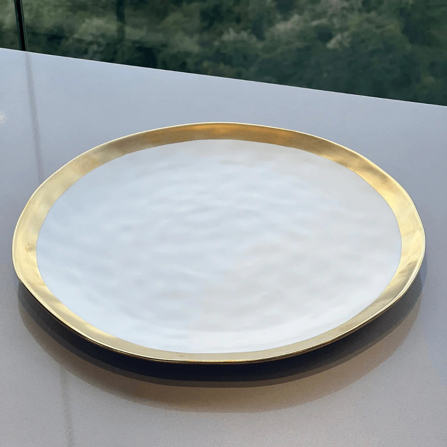 Prato raso branco com borda dourada texturizada visto de cima sobre superficie cinza