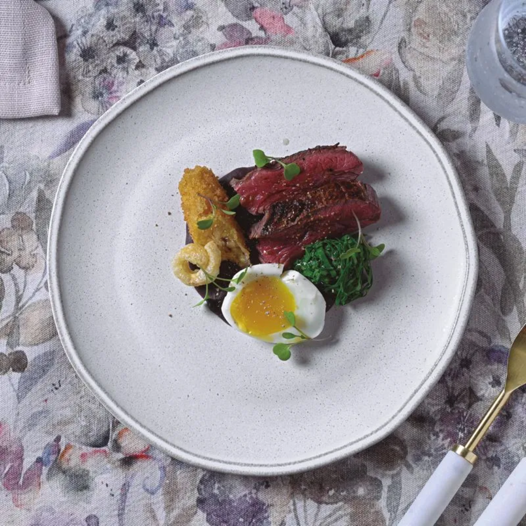 Prato branco com borda cinza servindo prato gourmet com proteína
