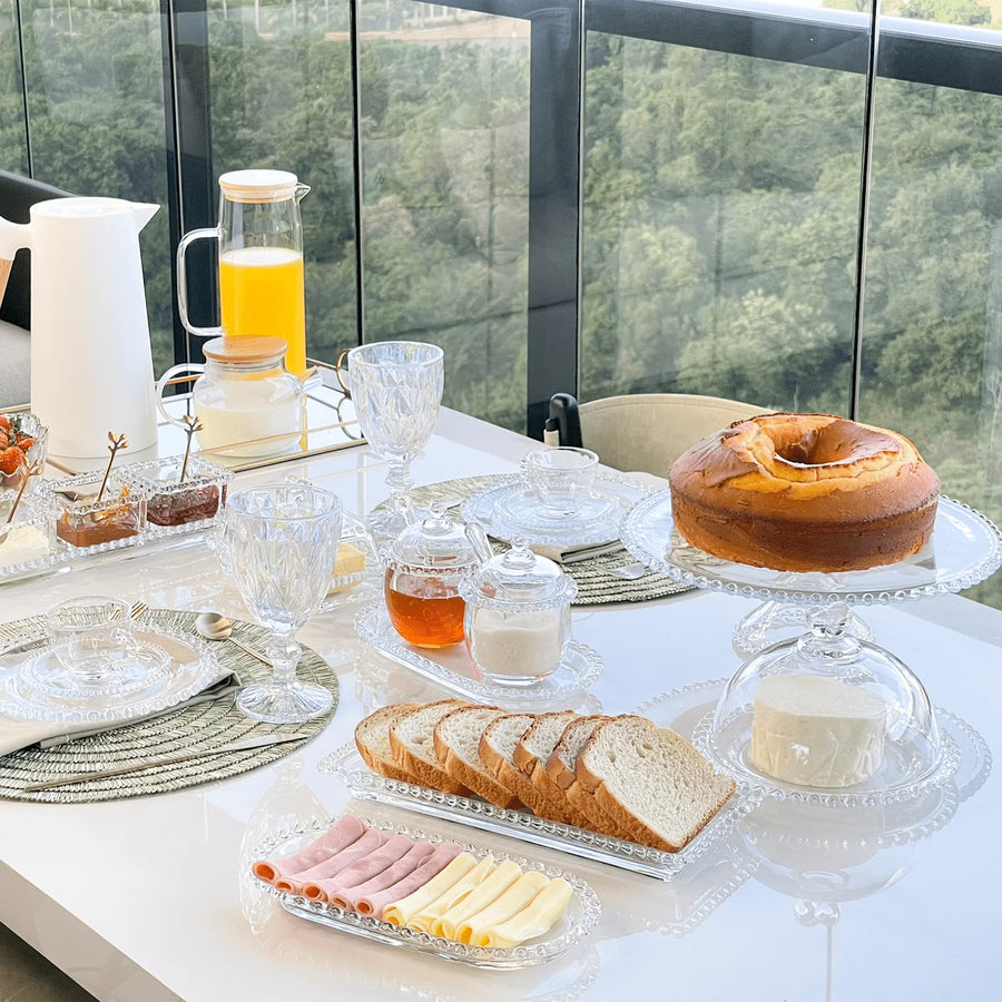 Mesa posta para cafe da manha com bolo frios sucos e pecas de cristal decoradas