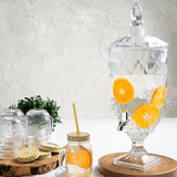 Suqueira transparente com pé e tampa de cristal com água saborizada de laranja