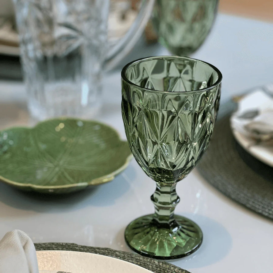 Taca de vidro verde com textura diamond em close sobre mesa elegante