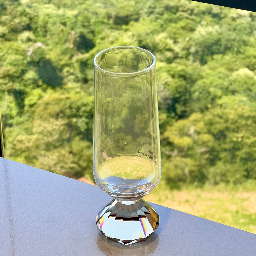 taca de vidro para champanhe com base diamante sobre mesa cinza