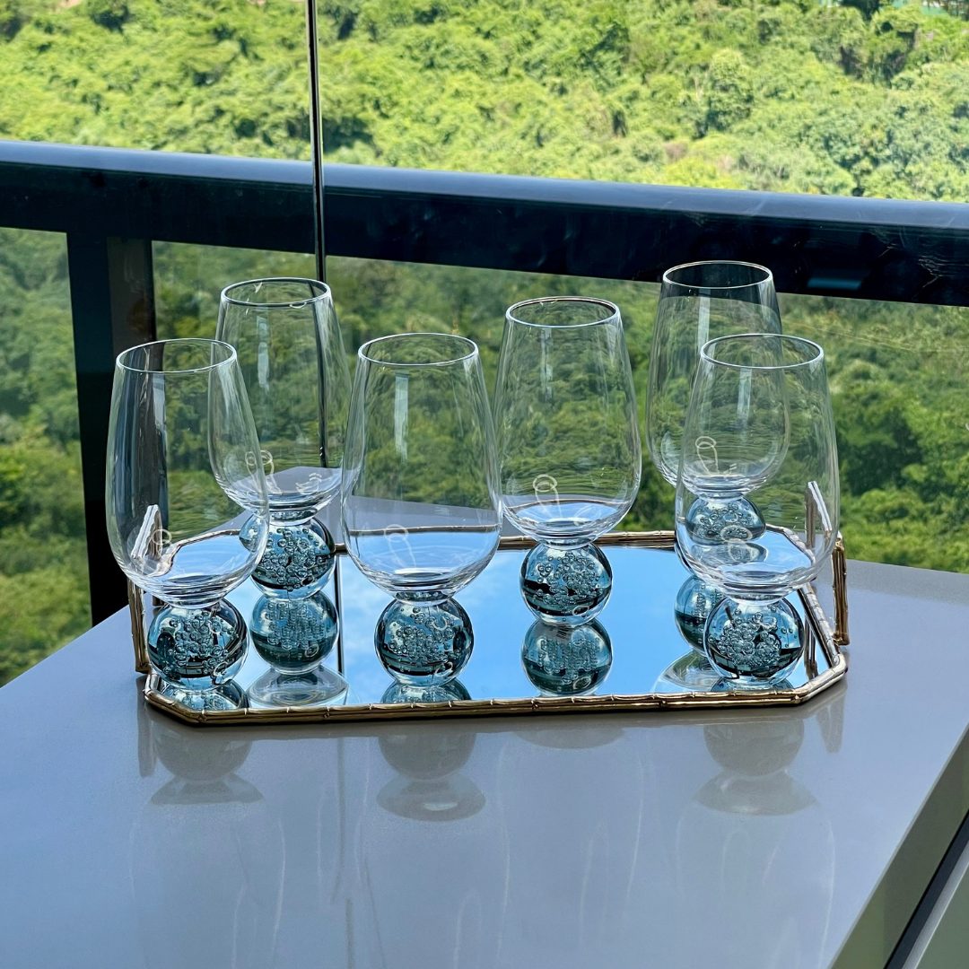 Jogo de tacas base esfera fume vistas de frente em bandeja espelhada com vegetacao ao fundo
