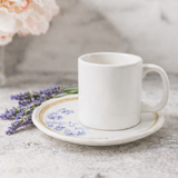 Xícara de café branca com pires azul Iris e lavanda decorativa