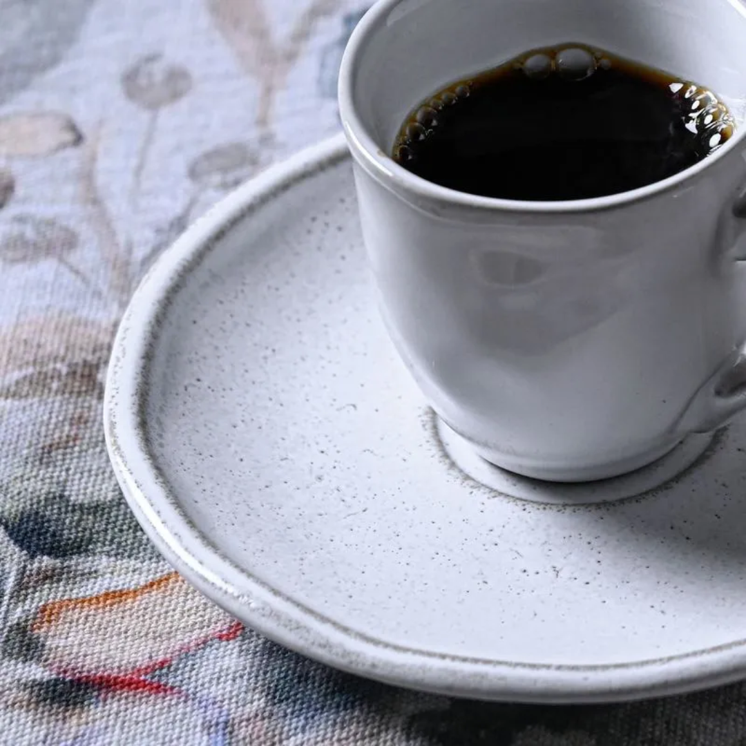 detalhe da textura granilhada do pires branco com xícara de cafe