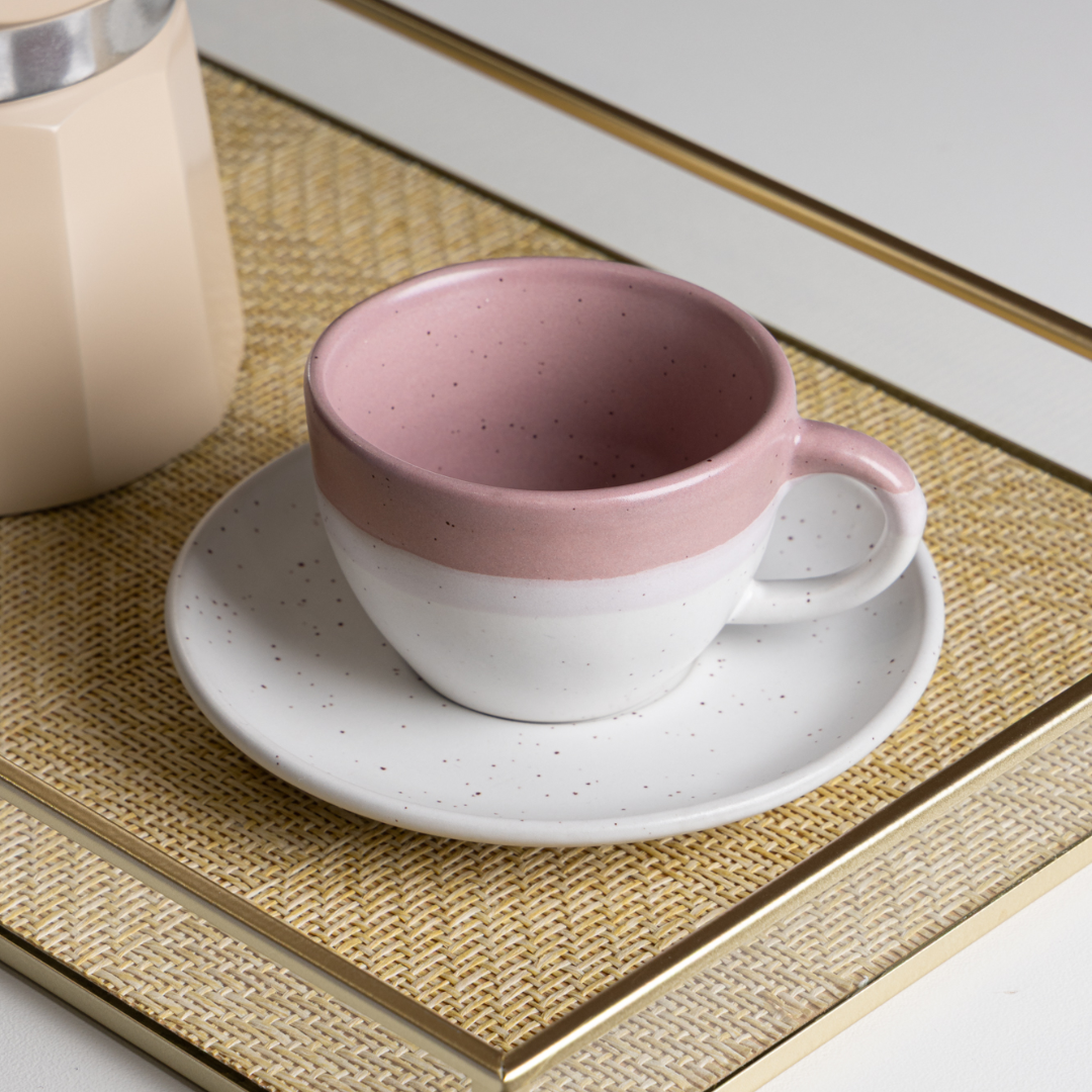 xicara ceramica rosa e branca sobre bandeja de palha dourada