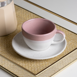 xicara ceramica rosa e branca sobre bandeja de palha dourada