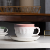 xícara cerâmica bicolor rosa e branco sobre pires em ambiente decorado