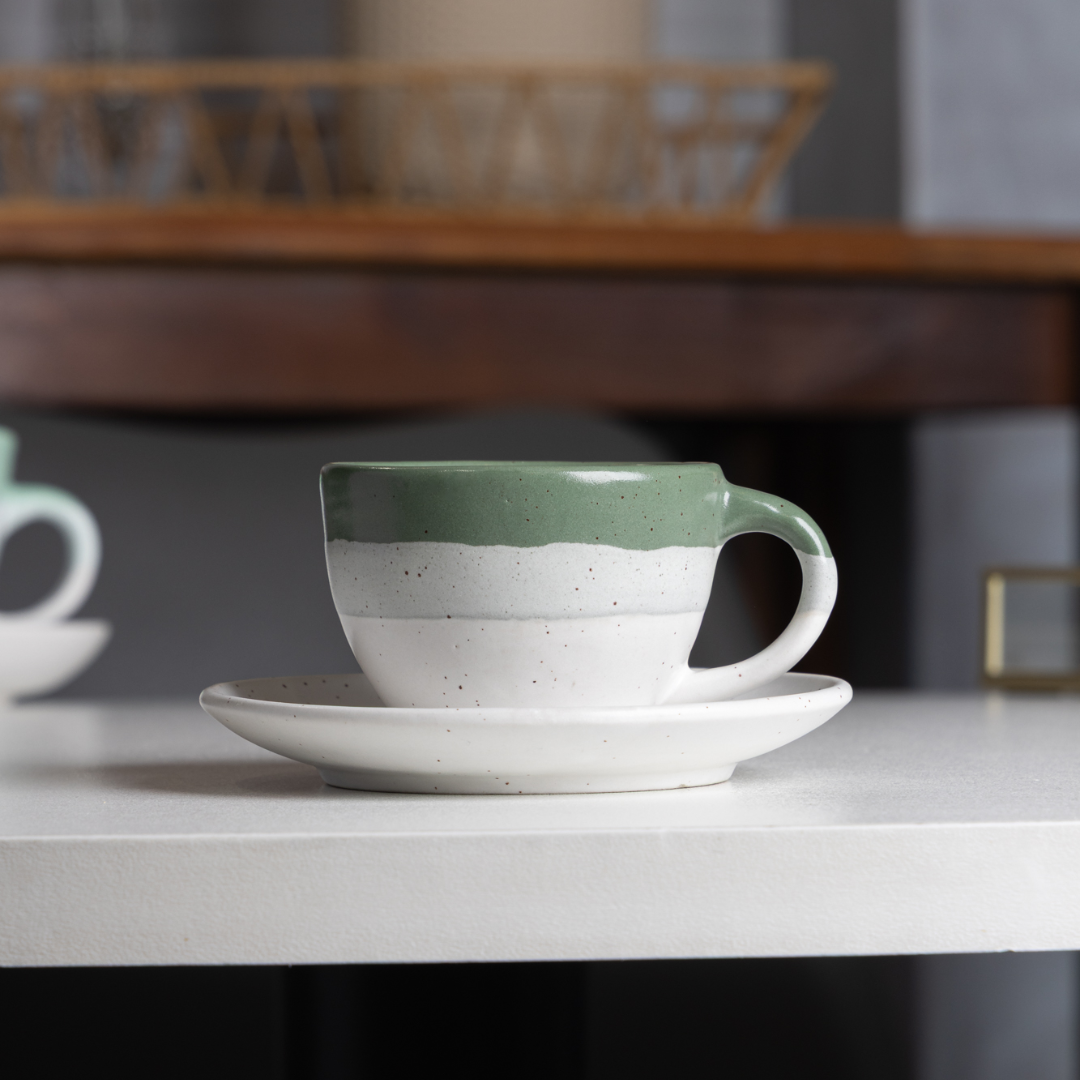 xícara com pires cerâmica bicolor verde e branco sobre prateleira decorada